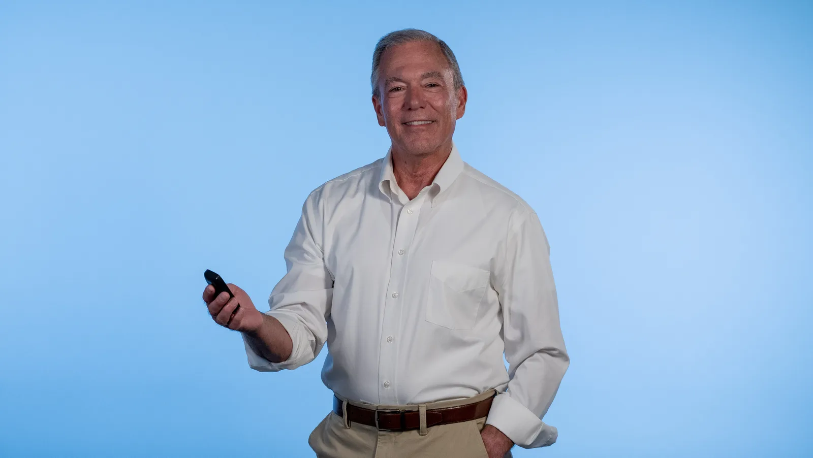 A smiling man holding up a glucose reader, with a CGM sensor on his upper arm